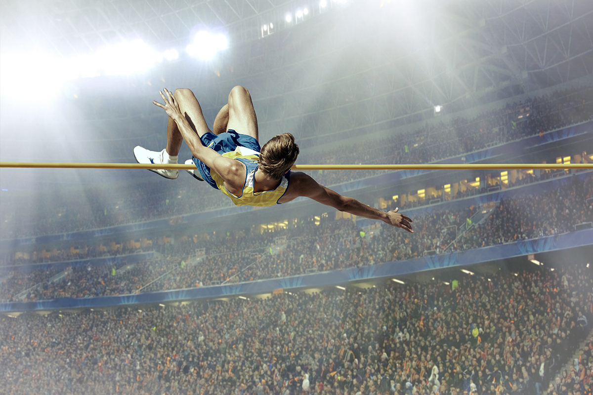 Portrait of young athlete jumping over a hurdle during training on race track.